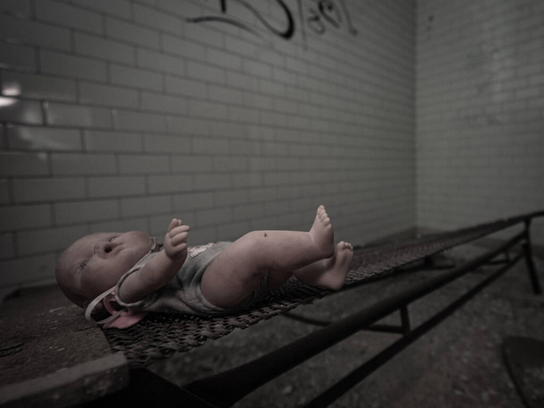 Egy elhagyatott pszichiátriai szobában elhagyott vintage baba. - Fotó, kép