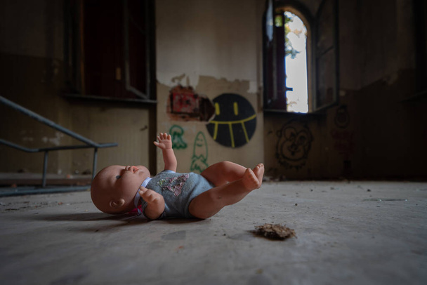 Terk edilmiş bir akıl hastanesinin odalarında terk edilmiş eski bir oyuncak bebek. - Fotoğraf, Görsel