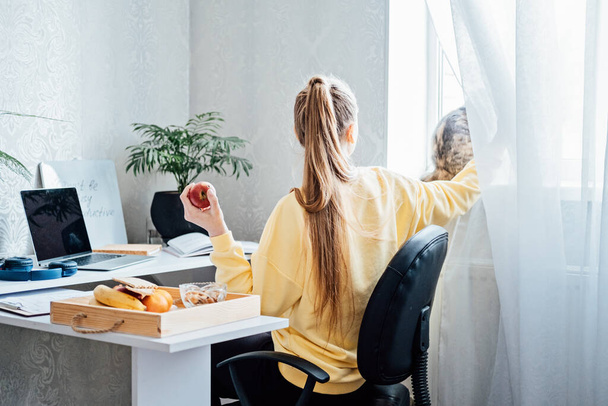 Eat Healthy While Working From Home. Healthy lunches work from home. Woman Freelancer eating Healthy Grain Snacks and fruits while working with laptop at home office - Foto, Imagem