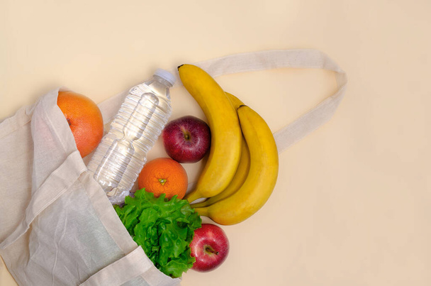 Torba z ekologicznej tkaniny, zakupy spożywcze, zdrowy styl życia. Owoce i butelka wody w lnianej torbie. Bawełniana torba. koncepcja odpadów zerowych - Zdjęcie, obraz