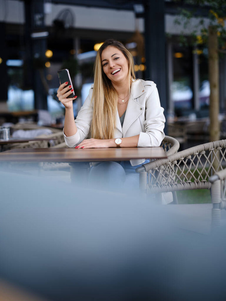 Eine schöne Frau sitzt im Café und bestellt Getränke über die mobile Anwendung. - Foto, Bild