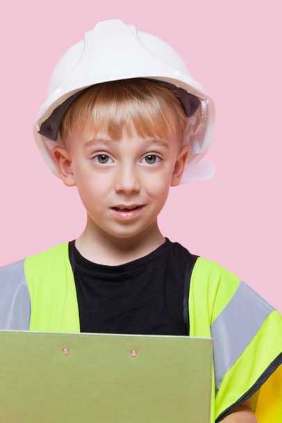 Retrato de um menino fingindo trabalhar na construção civil sobre fundo rosa - Foto, Imagem