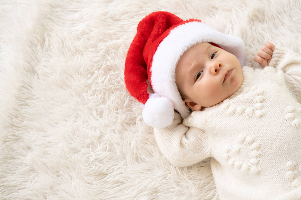 Christmas portrait of cute little newborn baby girl, wearing santa hat and hugging little cute snowman toy, winter time - 写真・画像