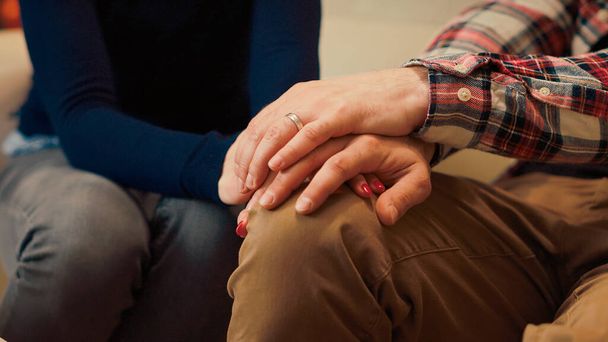 Man and woman holding hands after resolving relationship problems, feeling happy about reconciliation and making peace. Receiving counseling advice from therapist. Close up. Handheld shot. - Photo, Image