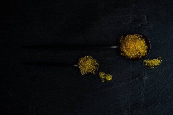Gelber Forellen-Kaviar auf schwarzem Hintergrund - Foto, Bild