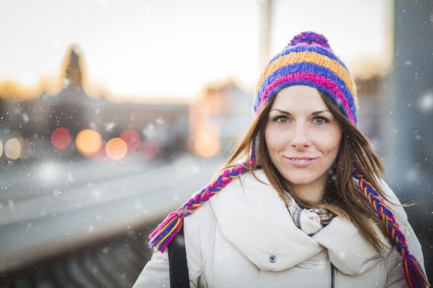 Positieve meisje met colorfull hoed in winter stad - Foto, afbeelding