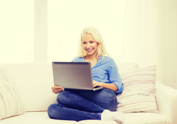smiling woman with laptop computer at home - Fotó, kép