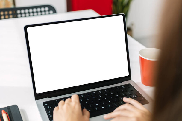 Simular la imagen de la joven mujer de negocios que trabaja en el ordenador portátil con pantalla blanca en blanco en la oficina moderna - Foto, imagen