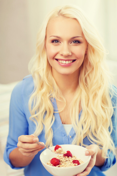 smiling woman with bowl of muesli having breakfast - Fotó, kép