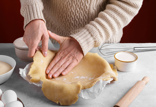 Donna disponendo l'impasto nella padella sulla tavola in cucina, le mani femminili stanno mettendo l'impasto torta crosta fatta in casa in una teglia. Fare una base per una torta frolla, torta del Ringraziamento - Foto, immagini