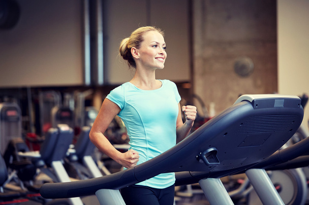 smiling woman exercising on treadmill in gym - Zdjęcie, obraz