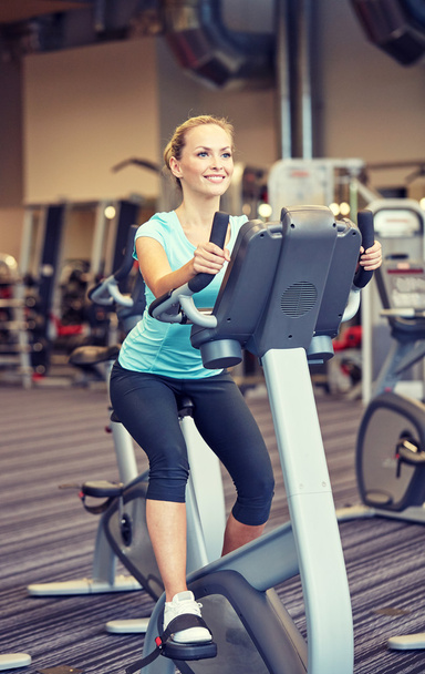 smiling woman exercising on exercise bike in gym - Фото, зображення