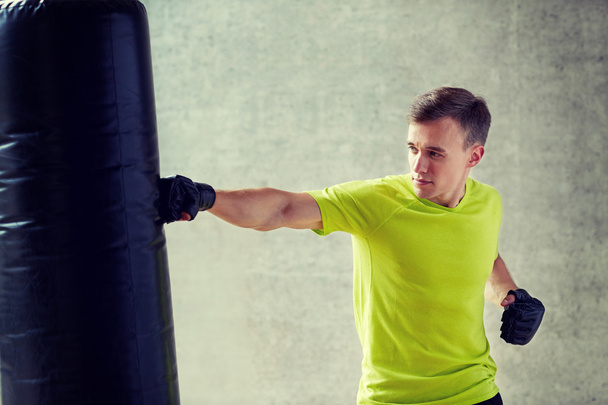 young man in gloves boxing with punching bag - Photo, Image