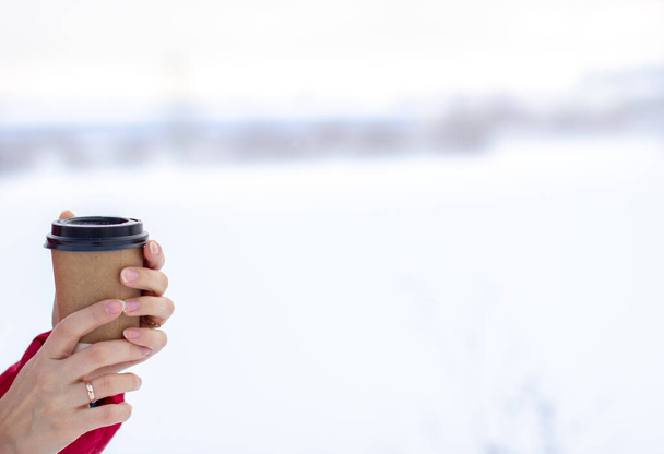 "Una giovane donna in inverno tiene un bicchiere di caffè caldo o tè" - Foto, immagini