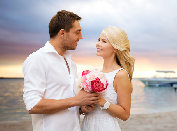happy couple with flowers over beach background - Fotoğraf, Görsel