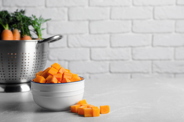 Bowl of fresh diced carrots on marble table. Space for text - Zdjęcie, obraz