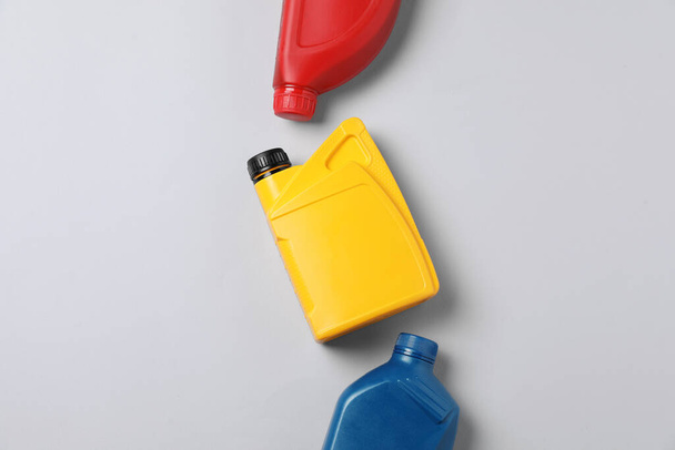 Motor oil in different canisters on light background, flat lay - 写真・画像