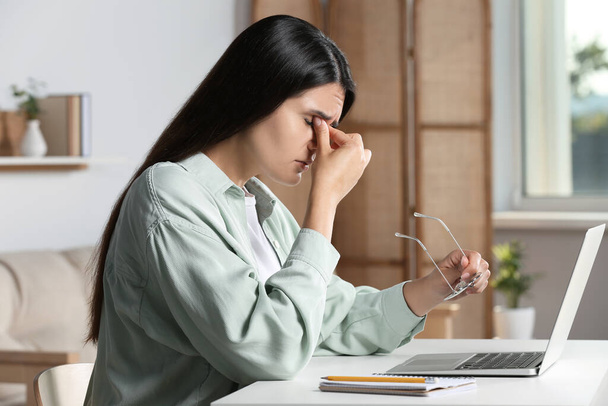 Young woman suffering from eyestrain at desk in office - Φωτογραφία, εικόνα
