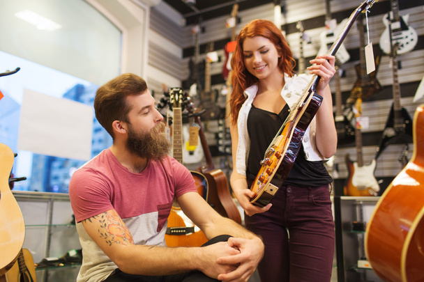couple of musicians with guitar at music store - Fotografie, Obrázek