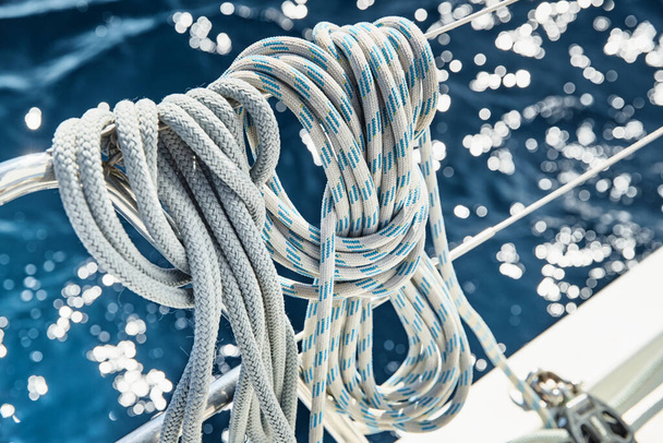 Close-up view of sailboat ropes at sunny weather, pulleys and ropes on the mast, Yachting sport, ship equipment, sea is on background - Photo, image