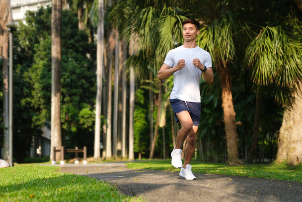 Przystojny młodzieniec biegający rano w parku miejskim. Koncepcja sprawności, zdrowego stylu życia, sportu i aktywności. - Zdjęcie, obraz