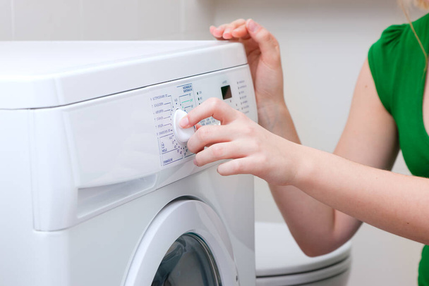 Женщина стирает одежду с помощью машины - Фото, изображение