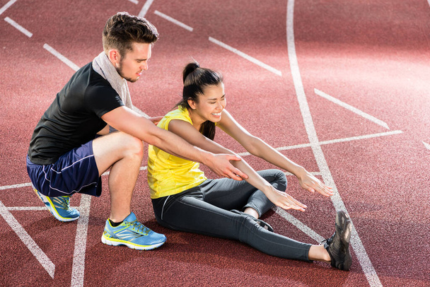 "Мужчина и женщина на шлаковом треке спортивной арены упражнения на растяжку
" - Фото, изображение
