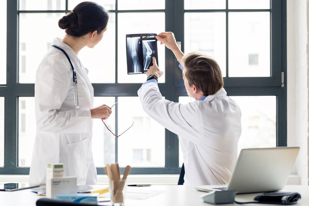 "Досвідчений ортопед допомагає колезі з інтерпретацією рентгенівського випромінювання в офісі" - Фото, зображення