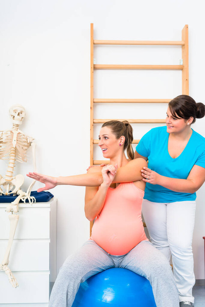 Mujer embarazada hace ejercicios de estiramiento con fisioterapeuta
 - Foto, Imagen