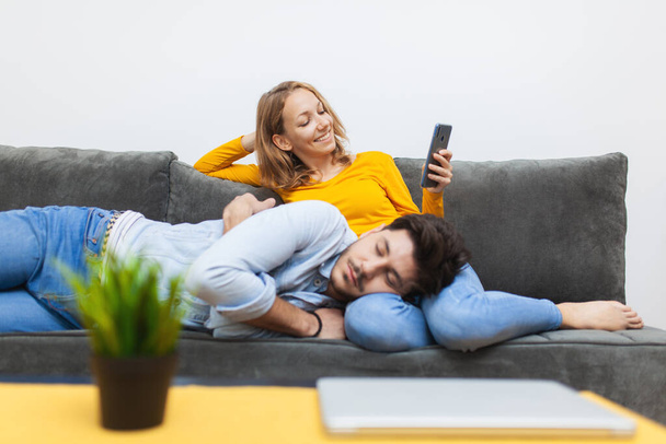 "jongen dutjes op schoot vriendin terwijl ze kijkt naar smart phone" - Foto, afbeelding