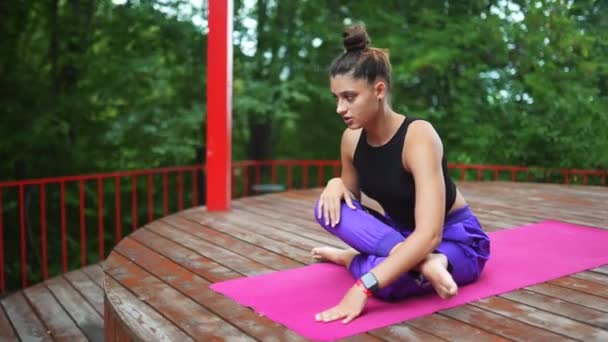 Een jonge vrouw in yoga in de tuin op de veranda - Video