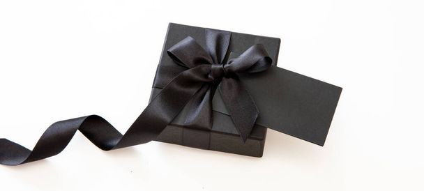 Black Friday Sale y regalos de Navidad. Caja de regalo con cinta negra y tarjeta vacía aislada sobre fondo blanco, - Foto, imagen