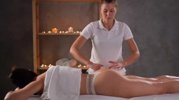 Beauty treatments for weight loss. masseur doing lymphatic drainage or anti cellulite massage on legs for woman client lying at spa center. Body care concept - Footage, Video