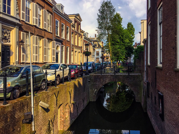 "橋と居心地の良い美しい家、車、自転車で通り昔の運河の素晴らしい景色。ユトレヒト、オランダ" - 写真・画像