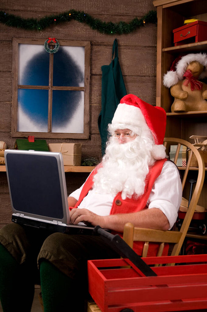 Santa Claus in Workshop Using Laptop - Photo, Image