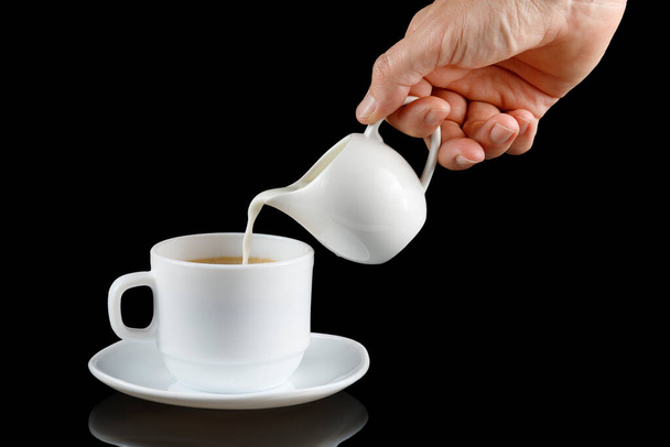 Kaffee mit Milch vorhanden. Milch wird in eine Tasse mit Kaffee gegossen. - Foto, Bild