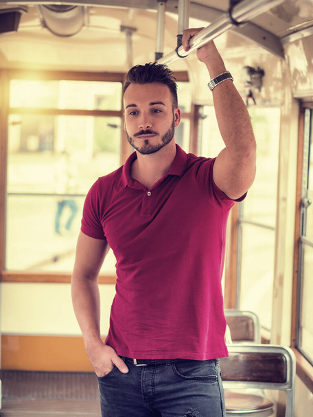 "Young handsome man riding on tram or old bus in city" - Foto, Bild