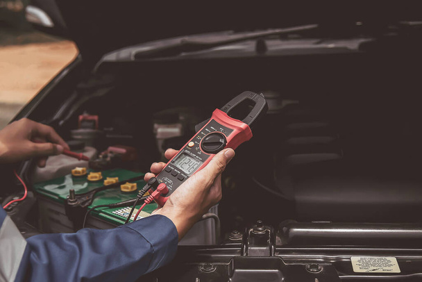 A technician is checking the car battery for availability. - Foto, imagen