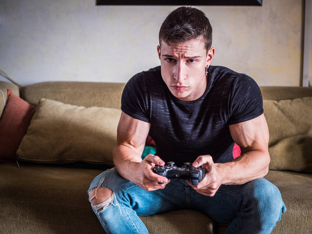 "Houkutteleva kaveri pelaa videopelejä joystick kädessä" - Valokuva, kuva