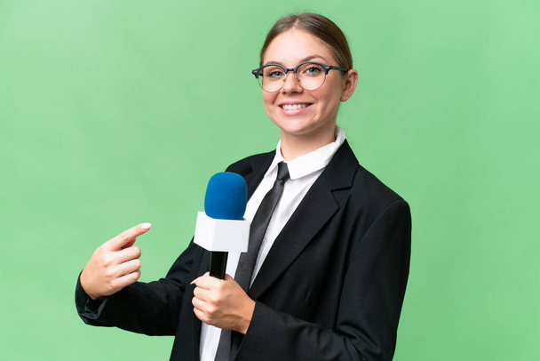 Jonge tv-presentator Kaukasische vrouw over geïsoleerde achtergrond en wijzen - Foto, afbeelding