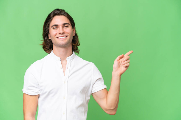 Young caucasian man isolated on green chroma background pointing finger to the side - Photo, Image