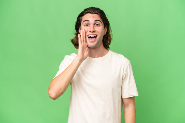 Young caucasian man isolated on green chroma background with surprise and shocked facial expression - Photo, Image