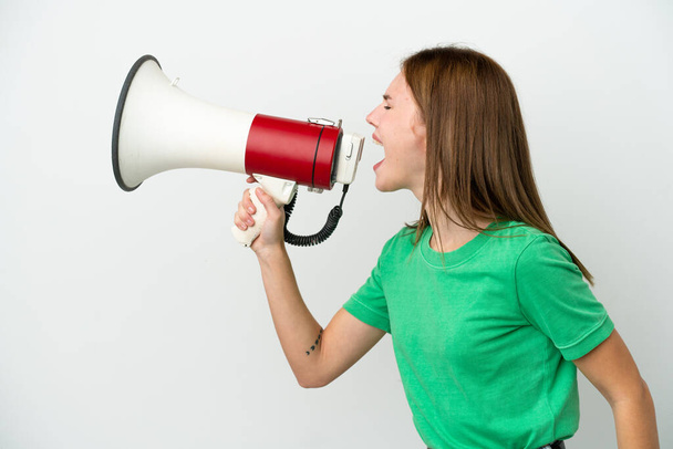 Giovane donna inglese isolata su sfondo bianco urlando attraverso un megafono per annunciare qualcosa in posizione laterale - Foto, immagini