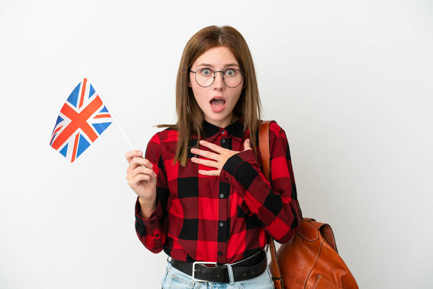 青い背景にイギリスの国旗を掲げた若い女性が驚いてショックを受けました。 - 写真・画像