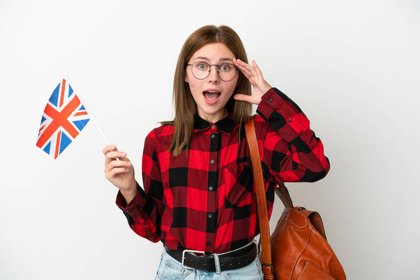 青い背景にイギリス国旗を掲げた若い女性が驚きの表情を見せる - 写真・画像