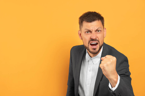 Aggressive man on orange background, space for text - Foto, Imagen