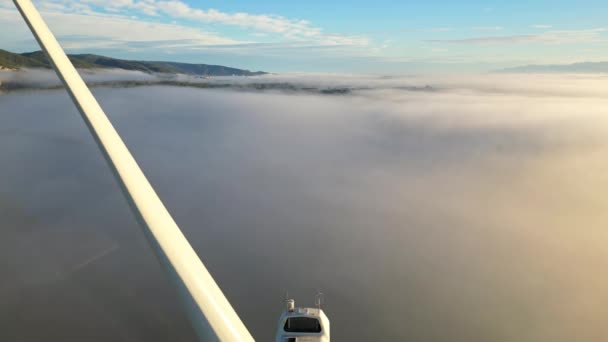 Drone shot wind turbine during sunrise dense morning fog. Close-up Wind turbines. Windmills producing clean green energy. - Footage, Video