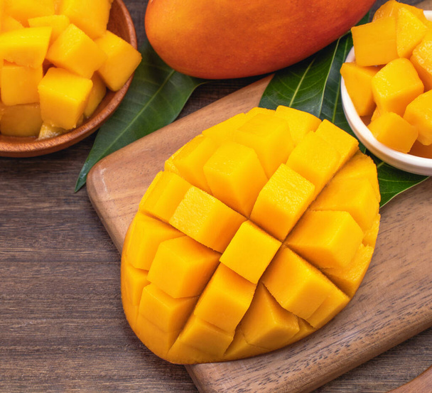 Fresh chopped mango cubes on wooden cutting board and rustic timber background. Tropical summer fruit concept, close up, macro, copy space.  - Photo, Image