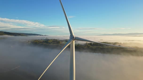 日の出高密度の朝の霧の間にドローンのショット風力タービン。クローズアップ風力タービン。クリーングリーンエネルギーを生産する風車. - 映像、動画
