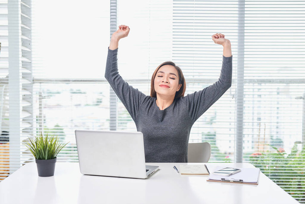 Satisfied woman relaxing with hands behind her head. Happy smiling employee after finish work, reading good news, break at work, girl doing simple exercise, relieve muscle stress, feeling well - Photo, Image